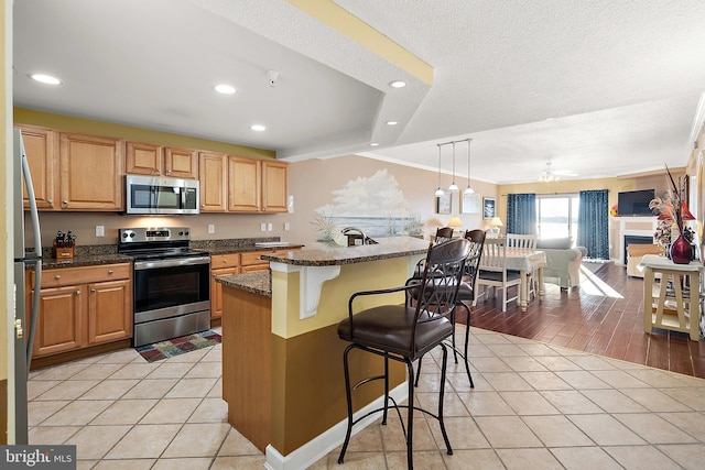 kitchen featuring appliances with stainless steel finishes, recessed lighting, a kitchen breakfast bar, light tile patterned flooring, and ceiling fan