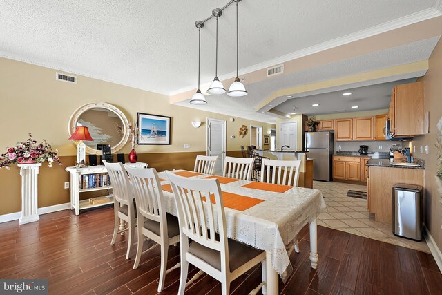 dining room featuring a textured ceiling, ornamental molding, wood finished floors, baseboards, and recessed lighting