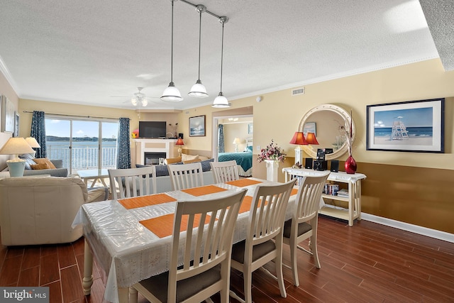 dining space featuring a textured ceiling, crown molding, wood finished floors, a ceiling fan, and baseboards