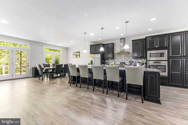 2660 Richmond Way, Hanover, MD 21076 - kitchen featuring stainless steel appliances, wall chimney range hood, a large island with sink, a breakfast bar, and light countertops