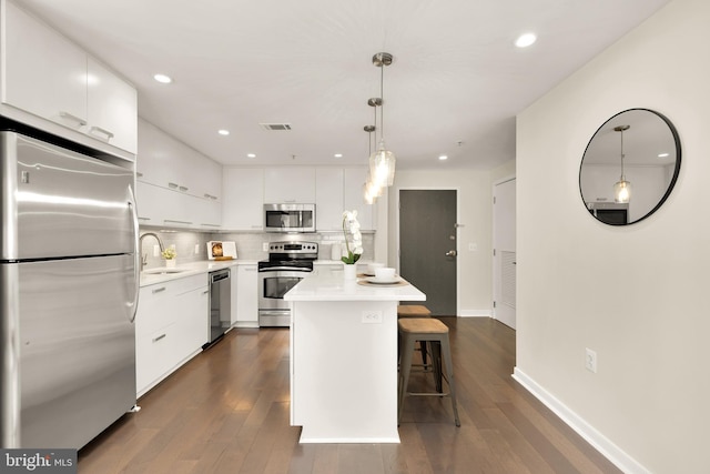 kitchen with stainless steel appliances, a sink, white cabinetry, dark wood-type flooring, and light countertops