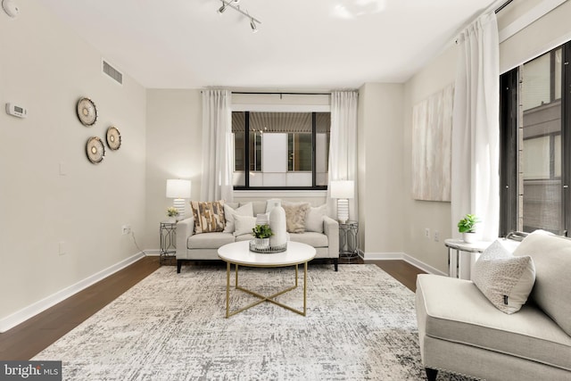 living area featuring baseboards, dark wood-style flooring, and rail lighting