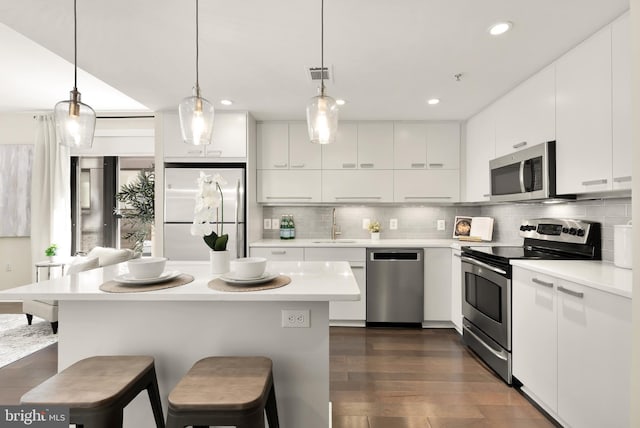 kitchen with stainless steel appliances, a breakfast bar, light countertops, tasteful backsplash, and recessed lighting