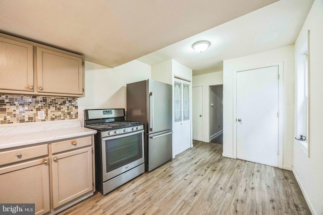 kitchen featuring stainless steel appliances, light wood-style floors, tasteful backsplash, and baseboards