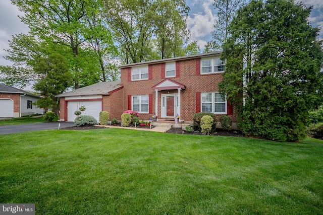 colonial house featuring a garage, driveway, a front lawn, and brick siding