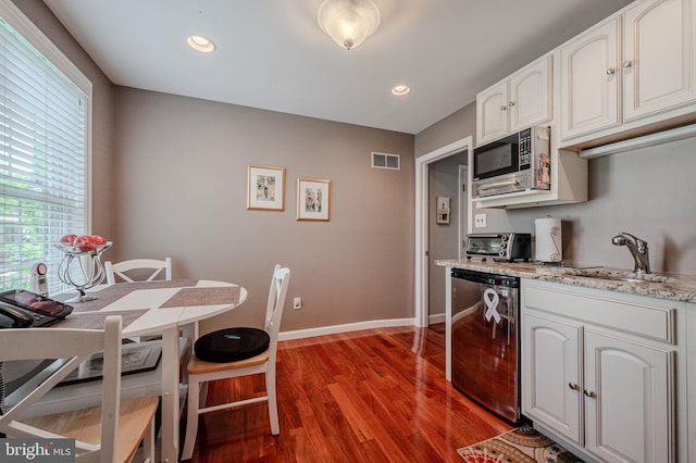 kitchen featuring appliances with stainless steel finishes, wood finished floors, a sink, baseboards, and white cabinets