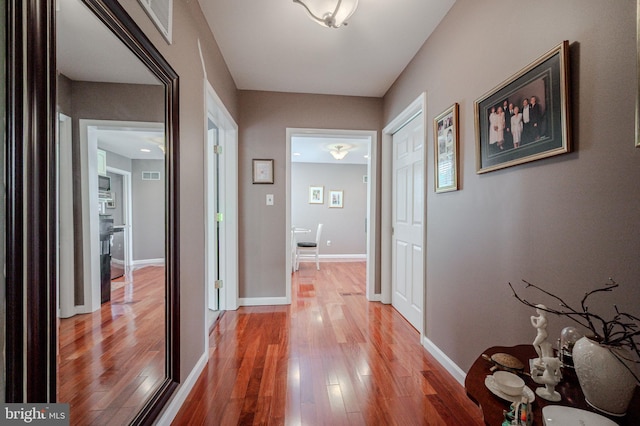 corridor with light wood-style flooring and baseboards