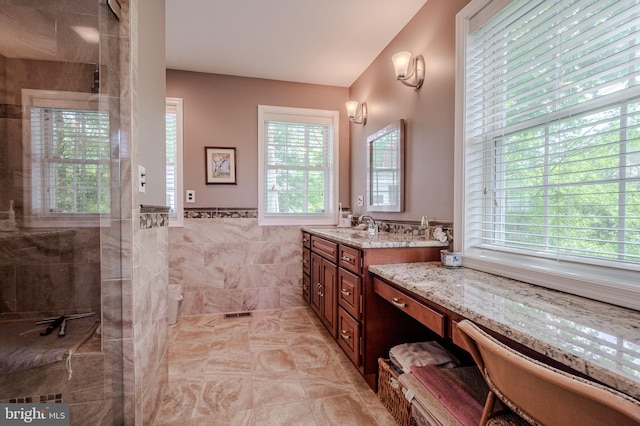 full bath featuring walk in shower, tile walls, vanity, wainscoting, and tile patterned flooring