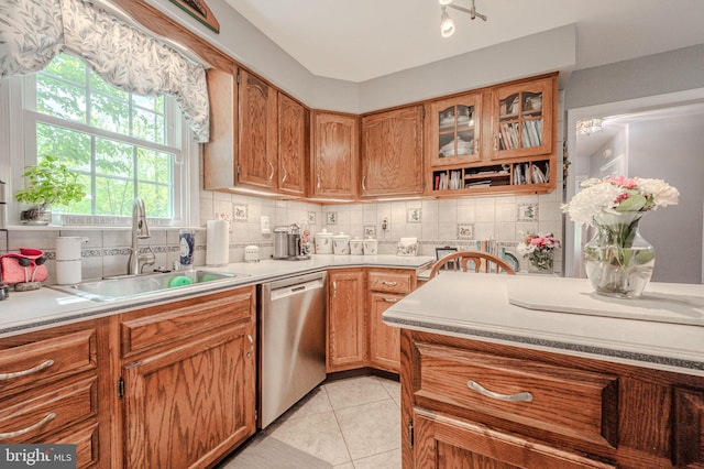 kitchen with dishwasher, a sink, tasteful backsplash, light tile patterned floors, and light countertops