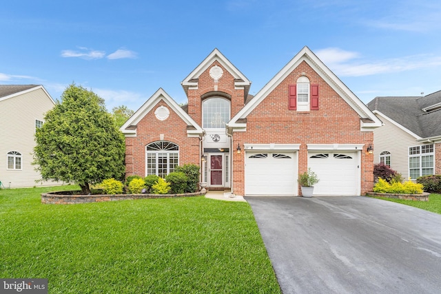 traditional-style home with driveway, brick siding, a front yard, and an attached garage