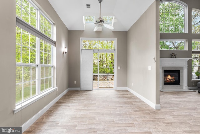 doorway featuring healthy amount of natural light, a high end fireplace, ceiling fan, baseboards, and lofted ceiling