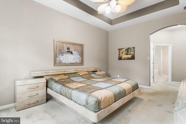 carpeted bedroom with arched walkways, baseboards, and connected bathroom