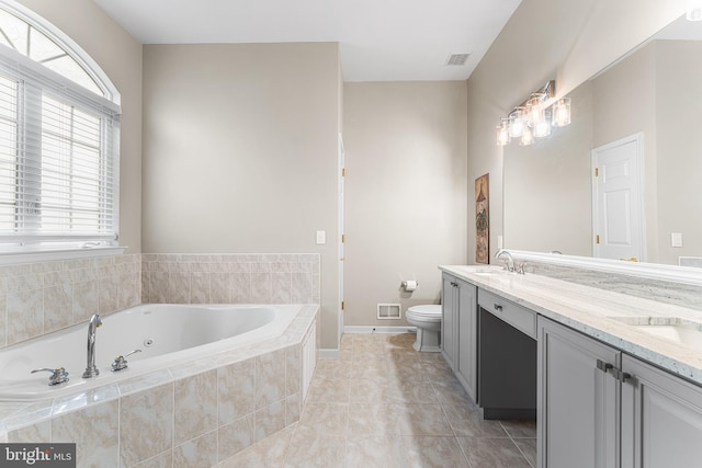 bathroom with toilet, plenty of natural light, a whirlpool tub, and double vanity