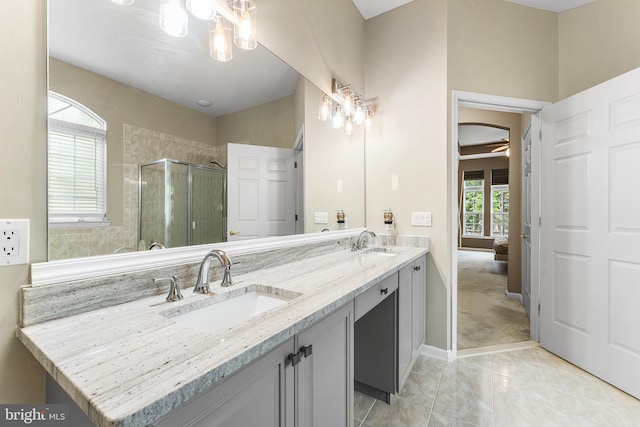 full bath featuring a shower stall, double vanity, and baseboards