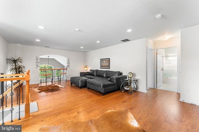 living room with light wood-style flooring, recessed lighting, baseboards, and arched walkways