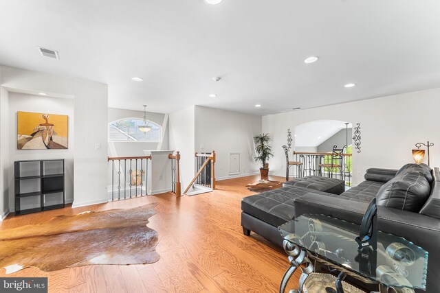 living area with recessed lighting, healthy amount of natural light, wood finished floors, arched walkways, and baseboards
