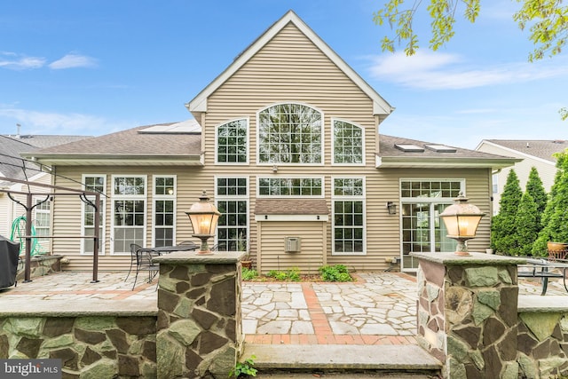 rear view of property featuring a patio and a shingled roof