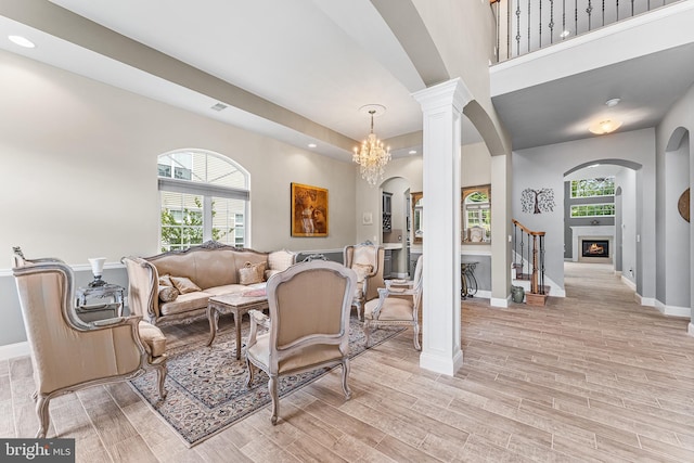 living area featuring arched walkways, healthy amount of natural light, baseboards, light wood-type flooring, and recessed lighting