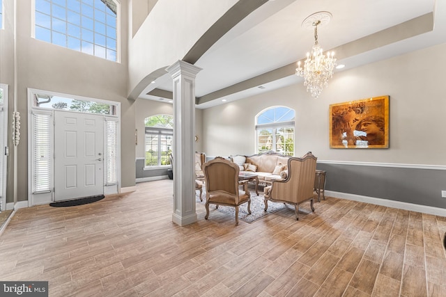 foyer entrance with ornate columns, baseboards, wood finished floors, plenty of natural light, and a high ceiling