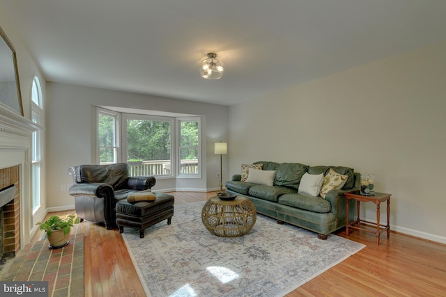 living area with a brick fireplace, plenty of natural light, and wood finished floors