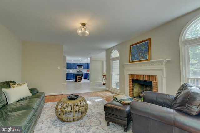 living room featuring a fireplace, light wood-type flooring, and baseboards