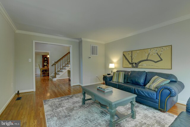 living area with crown molding, stairway, wood finished floors, and baseboards