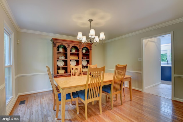 dining area featuring light wood-style floors, a chandelier, crown molding, and baseboards