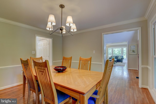 dining room featuring a chandelier, light wood-type flooring, ornamental molding, and baseboards