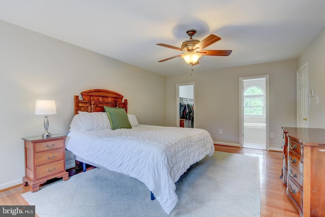 bedroom featuring light wood-style flooring, a spacious closet, and baseboards