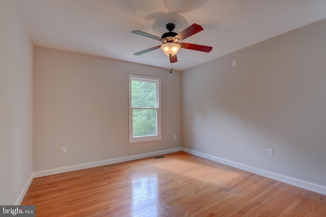 spare room with ceiling fan, light wood-style floors, and baseboards