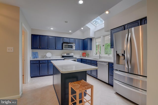 kitchen with stainless steel appliances, blue cabinetry, a center island, a sink, and light tile patterned flooring