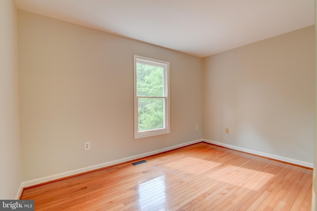 spare room featuring hardwood / wood-style flooring and baseboards