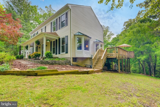 rear view of property with a yard, stairs, and a deck
