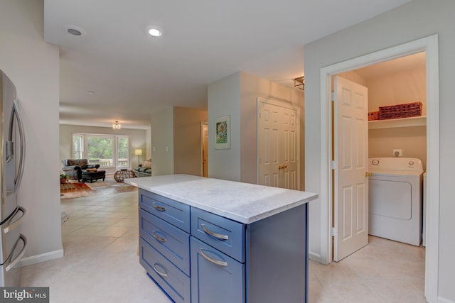 kitchen featuring washer / dryer, blue cabinets, open floor plan, stainless steel fridge with ice dispenser, and light tile patterned floors