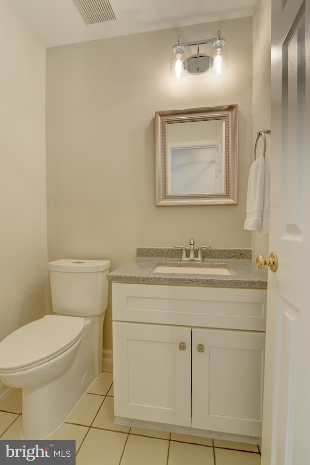 half bath with tile patterned flooring, vanity, and toilet