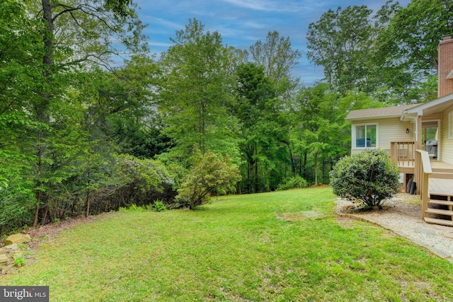 view of green lawn featuring a wooden deck