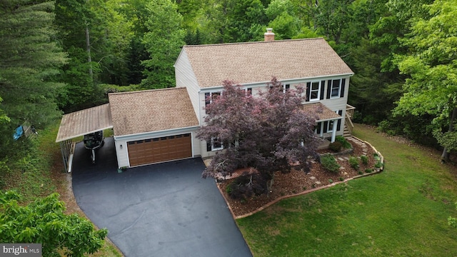 view of front facade featuring asphalt driveway, a chimney, a forest view, a carport, and a front lawn