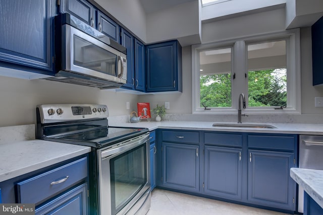 kitchen with appliances with stainless steel finishes, a sink, and blue cabinetry