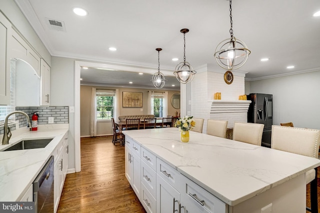 kitchen with a sink, stainless steel dishwasher, black fridge, recessed lighting, and white cabinets