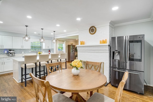 dining room featuring crown molding, light wood-type flooring, and recessed lighting