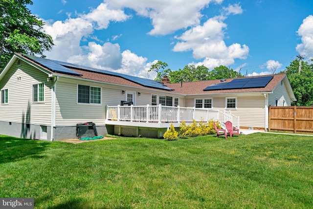 back of house with a wooden deck, solar panels, and a chimney