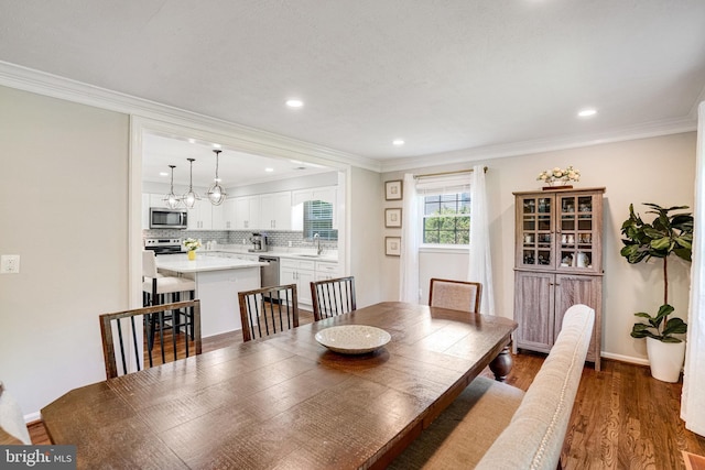 dining room featuring wood finished floors, ornamental molding, recessed lighting, and baseboards