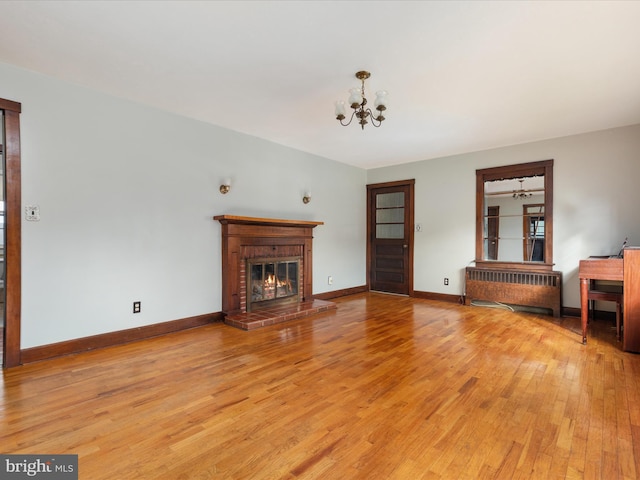 826 W 16th St, Front Royal, VA 22630 - unfurnished living room with radiator, light wood-style floors, a chandelier, a fireplace, and baseboards