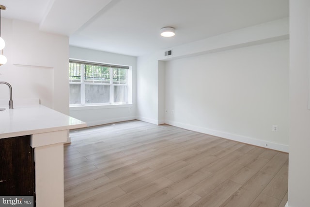 unfurnished living room featuring light wood-type flooring and baseboards