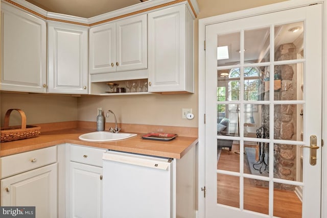 kitchen featuring dishwasher, a sink, light countertops, white cabinets, and open shelves