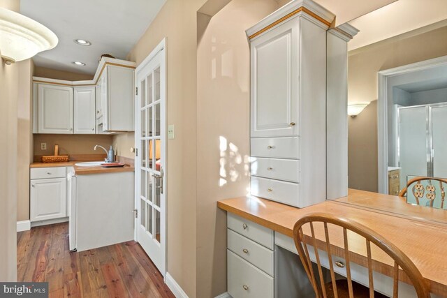 kitchen with dark wood-style floors, a sink, recessed lighting, white cabinets, and baseboards