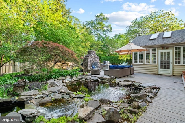 deck featuring a garden pond, fence, and an outdoor living space with a fireplace