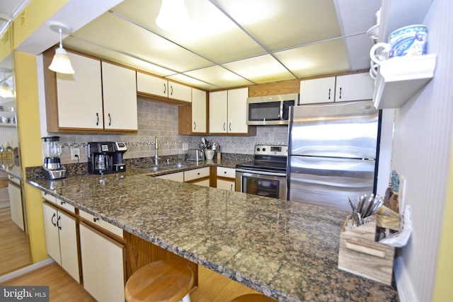 107 Convention Center Dr Unit 148D, Ocean City, MD 21842 - kitchen with stainless steel appliances, a sink, a peninsula, decorative backsplash, and hanging light fixtures