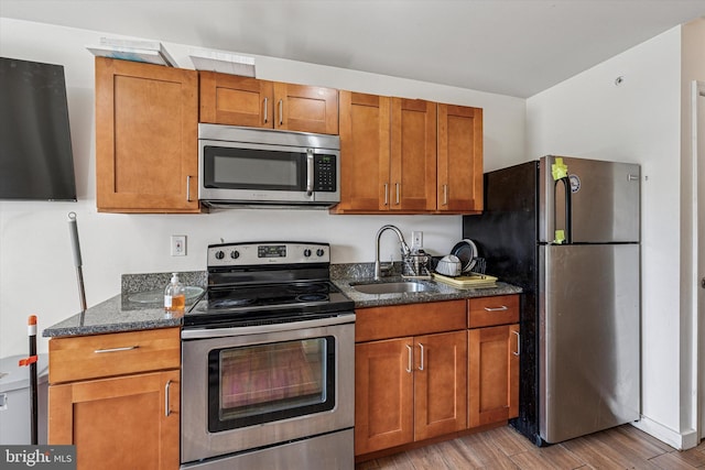 1934 Cecil B Moore Ave, Philadelphia, PA 19121 - kitchen with stainless steel appliances, a sink, dark stone countertops, light wood-style floors, and brown cabinets