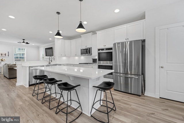 kitchen featuring stainless steel appliances, light countertops, white cabinetry, light wood finished floors, and a peninsula